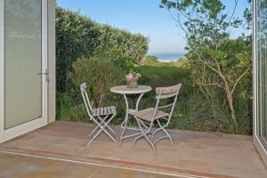 una mesa y sillas en un patio con vistas al océano en Mosselberg on Grotto Beach en Hermanus