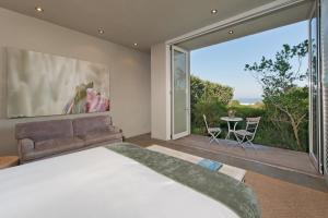 - une chambre avec un grand lit et une grande fenêtre dans l'établissement Mosselberg on Grotto Beach, à Hermanus
