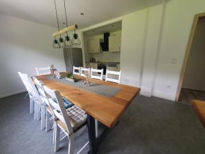 a dining room with a wooden table and white chairs at Ferienhaus Tüchersfeld in Pottenstein