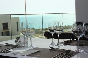 a table with wine glasses and a view of the ocean at Amphora Hotel & Suites in Paphos
