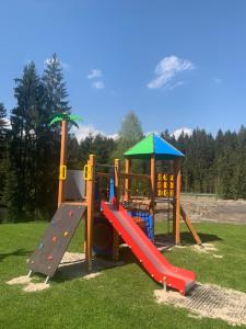 um parque infantil com um escorrega e uma estrutura de brincar em Olza Karczma i pokoje em Istebna