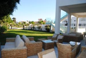 a patio with wicker chairs and tables and a lawn at Amphora Hotel & Suites in Paphos