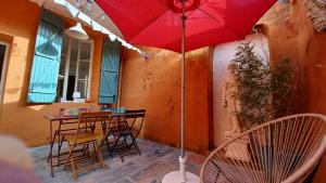 a red umbrella on a patio with chairs and a table at MAISON DE CHARME AVEC COUR, proche rue des Teinturiers in Avignon +18 photos