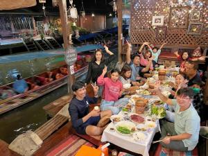 een groep mensen die aan een tafel eten bij Baanklong Amphawa Homestay in Amphawa