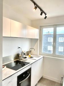 a kitchen with white cabinets and a window at les suites du beffroi 2 in Calais