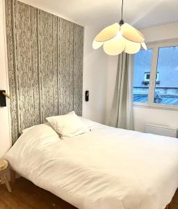 a white bed in a room with a window at les suites du beffroi 2 in Calais