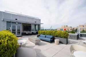 a patio with a blue couch and tables and chairs at Stylish Condo at Clarendon with Rooftop Views in Arlington