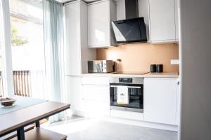 cocina con armarios blancos y mesa en Luxurious Apartment with South facing Garden, en Perth