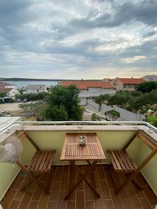 een balkon met een houten tafel en 2 stoelen bij Apartmani Begic 1 i 2 in Barbat na Rabu