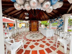 Habitación con sillas y mesas blancas y techo con globos. en Casa Campestre La Colombiana, en Montenegro