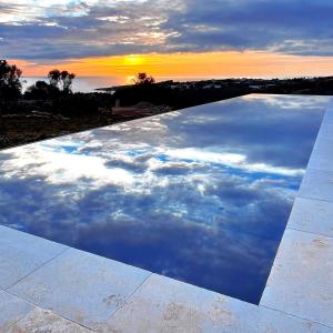 a pool of water with a sunset in the sky at Villa CREA in Marina di Leuca