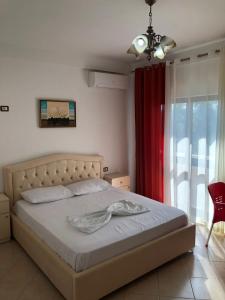 a bedroom with a bed and a red curtain at Vila Vera in Durrës
