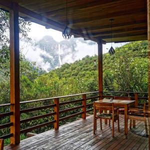 drewniany ganek ze stołem i widokiem na góry w obiekcie Goctamarca Lodge w mieście Cocachimba