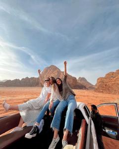 Tre persone sedute sul retro di un camion nel deserto di stars magic camp a Wadi Rum