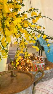 um vaso com flores amarelas e luzes numa mesa em SENSI - 'FIRE' Restaurant and Glamping em Oostkamp