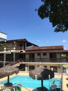 a hotel with a swimming pool and two umbrellas at Hotel Pousada Guayporã in Guarapari