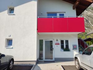 Biały dom z czerwonym dachem i drzwiami w obiekcie Pan Haus Bad Goisern w mieście Bad Goisern