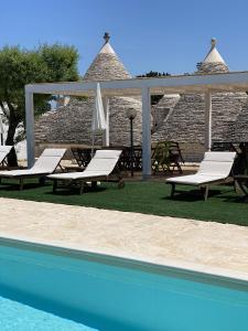 阿爾貝羅貝洛的住宿－i Trulli del Fauno，一组躺椅和一个游泳池
