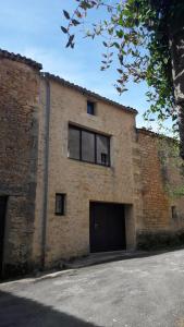 um edifício de tijolos com duas portas de garagem e uma janela em Grande maison de ville avec cheminée et loggia em Lacapelle-Biron