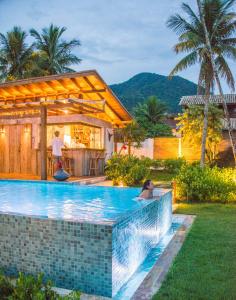 a woman sitting in a swimming pool in a house at Villa Sapê Pousada in Ubatuba