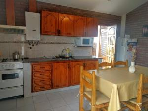 a kitchen with wooden cabinets and a table with chairs at Cabañas Bosque in Villa Carlos Paz