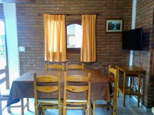 ein Esszimmer mit einem Tisch, Stühlen und einem TV in der Unterkunft Cabañas Bosque in Villa Carlos Paz