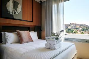 a bedroom with a bed with towels and a window at Urban Frame Plaka in Athens