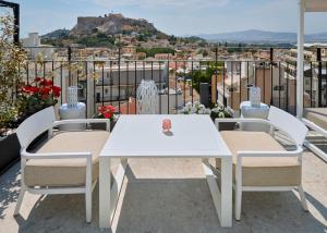 d'une table et de chaises blanches sur un balcon avec vue. dans l'établissement Urban Frame Plaka, à Athènes