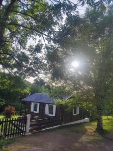 a small house with a fence and a tree at les chalets de l'essentiel in Lacaze