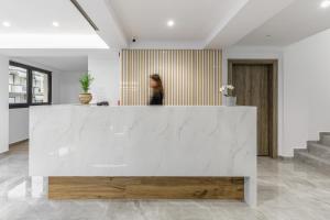 a woman is standing behind a white counter in a room at Anassa Suites in Leptokaria