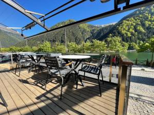 a deck with tables and chairs and a view of a lake at Ozkan Otel in Uzungöl