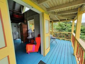 eine Veranda eines Hauses mit einem roten Stuhl darauf in der Unterkunft Traditional West Indian cottage on Good Moon Farm in Great Mountain