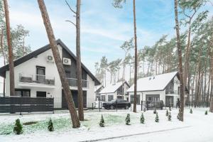 Une rangée de maisons dans la neige avec des arbres dans l'établissement Dziwnówek Apartament Horizon Park 4A, à Dziwnówek