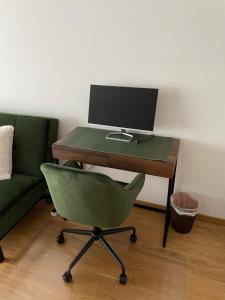 einen Schreibtisch mit einem Computermonitor und einem grünen Stuhl in der Unterkunft Studio Stevie Nicks I Workplace I 24in Screen I Kitchen I PS4 in Offenbach