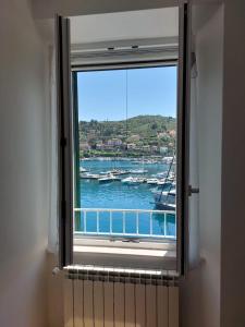 okno z widokiem na łódź w wodzie w obiekcie Casa della Nonna casevacanzeargentario w mieście Porto Santo Stefano