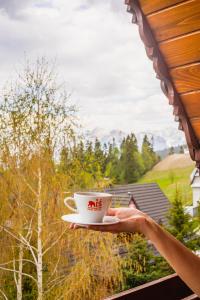 een persoon met een kopje koffie op een balkon bij Miś Pokoje Gościnne in Bukowina Tatrzańska