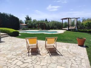 two chairs sitting on a patio next to a pool at Villa Traditional Estate Heated Pool & Garden, 5 bedrooms in Metókhion Patriotikón