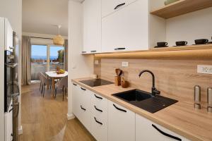 een keuken met witte kasten, een wastafel en een tafel bij Sun Spalato Adris in Split