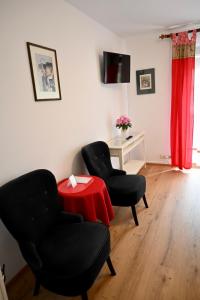a living room with two chairs and a red table at Hotel Am Rupertuspark in Bad Reichenhall