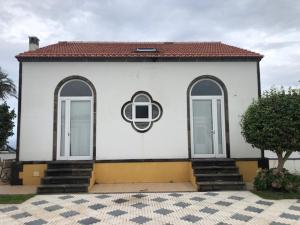 ein weißes Gebäude mit zwei Fenstern und einem Dach in der Unterkunft A QUINTA DAS FLORES- Casa do Miradouro in Santa Cruz das Flores