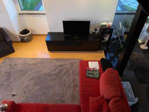 a living room with a red couch and a tv at A QUINTA DAS FLORES- Casa do Miradouro in Santa Cruz das Flores