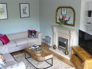 sala de estar con sofá blanco y chimenea en Woodburn ground-floor apartment in quiet setting in Pitlochry, en Pitlochry