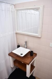 La salle de bains est pourvue d'un lavabo blanc et d'une fenêtre. dans l'établissement la mas linda ventana al mar, à Puerto Madryn