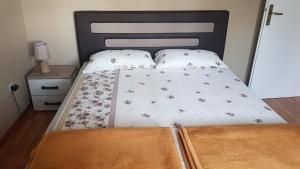 een bed met een zwart hoofdeinde en 2 witte kussens bij Apartment Lidija in Herceg-Novi