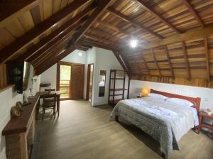 モンテ・ヴェルデにあるPousada Recanto do Sauá - Monte Verdeのベッドルーム1室(ベッド1台、テーブル付)、キッチン