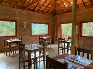 una sala da pranzo con tavoli, sedie e finestre di Pousada Recanto do Sauá - Monte Verde a Monte Verde