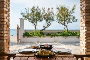 a table with a plate of food and wine glasses at Tamaris Beach House in Acharavi