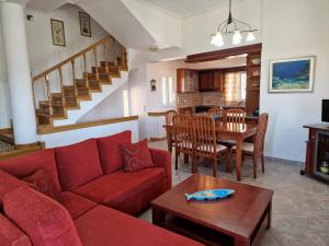 sala de estar con sofá rojo y mesa en The Mirador Boutique Villa with Scenic Sea View, en Porto Rafti