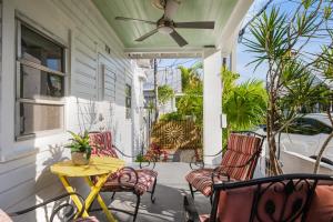a porch with chairs and a table and a ceiling fan at Tropic Dream in Key West