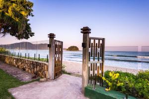 um portão na praia com o oceano atrás dele em Villa Sapê Pousada em Ubatuba